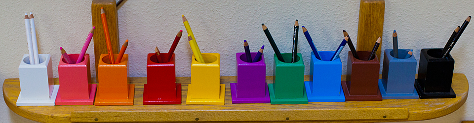 colorful containers hold colored pencils on a shelf in the Philomath Montessori School classroom
